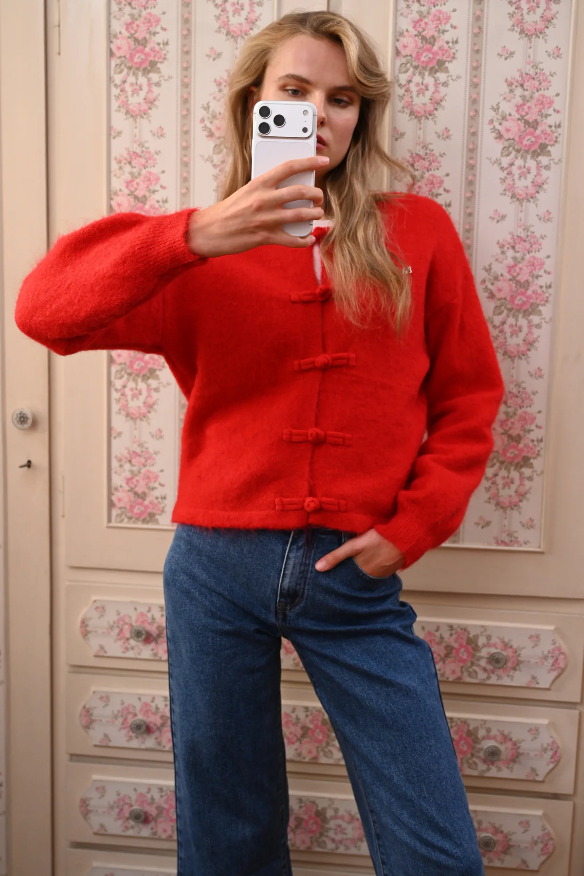 Boom Loulou red knit cardigan – close-up of the knotted loop fastenings, metallic bow and ribbed cuffs