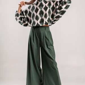 Teta Arvanitaki Milan green pants, full-length front view styled with a patterned blouse and black boots.