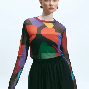 The Norm Kukka printed mesh top tucked into a black skirt, front styling view