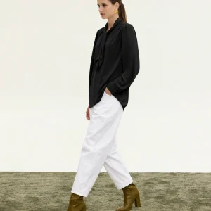 Innocent Estelle Tie-Neck Top in black on model, walking view showing neck tie and long sleeves