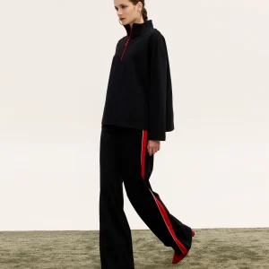 Innocent Raven black top and pants on model walking, showing red side stripe with white edging on pants
