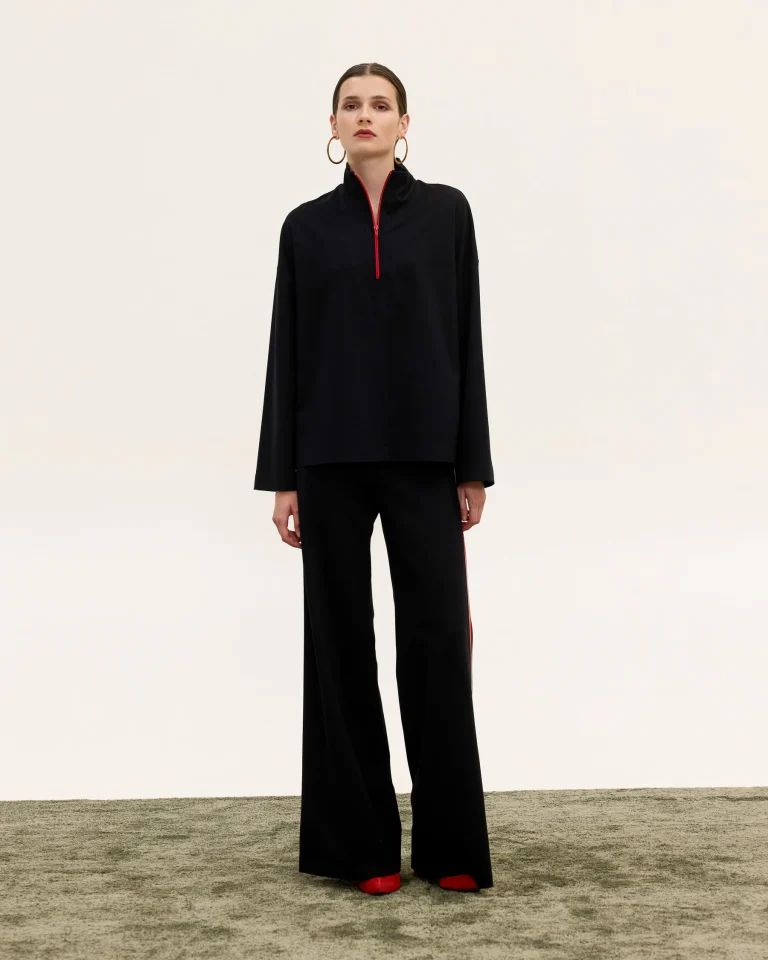 Innocent Raven black top and pants on model, front view showing red zip on top and wide-leg pants