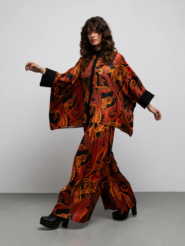 Pearl Paisley Black kaftan shirt by We Are worn with matching Midler pants, walking view with arms extended